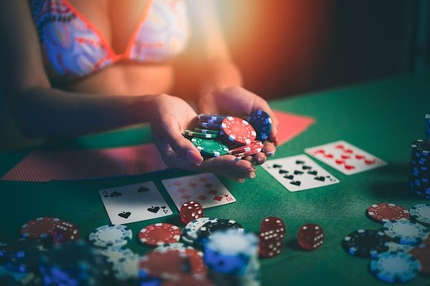 Photo woman wearing bikini dealer or croupier shuffles poker cards in a casino on the background of a tableasain woman holding chips casino poker poker game concept